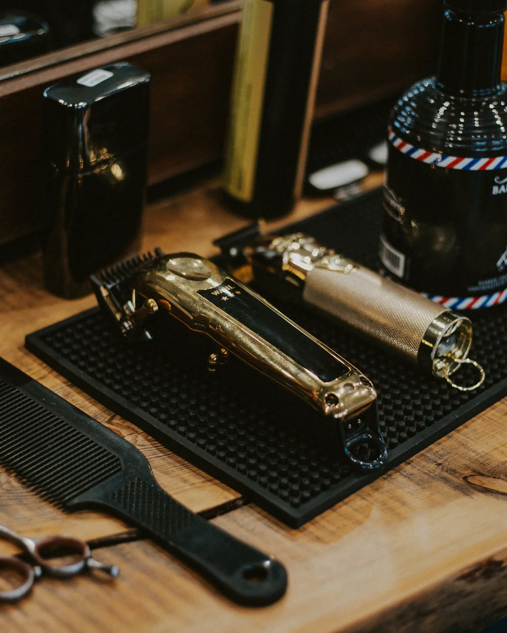 Tondeuse dorée, peigne et ciseaux posés sur le plan de travail du barbier